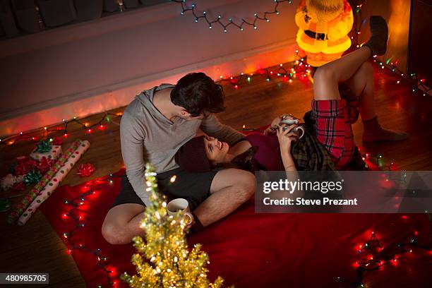 young couple relaxing in sitting room at christmas - santa in shorts stock pictures, royalty-free photos & images