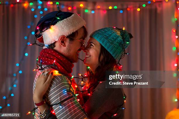 romantic young couple wrapped in decorative lights at christmas - christmas couple foto e immagini stock