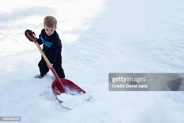 male toddler digging snow with large shovel - kid in big shoes stock pictures, royalty-free photos & images