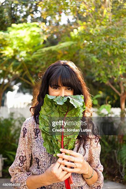 portrait of young woman holding vegetable leaf - blette photos et images de collection