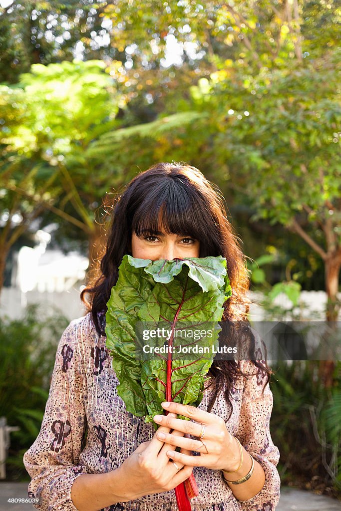 Portrait of young woman holding vegetable leaf