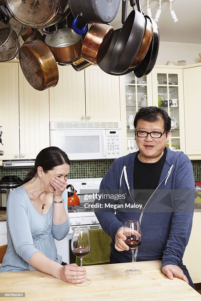 Mature couple relaxing with a glass of wine in kitchen