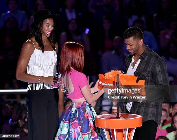 Player Russell Wilson accepts the King of Swag and Best Cannon awards from WNBA player Candace Parker and figure skater Ashley Wagner onstage at the...