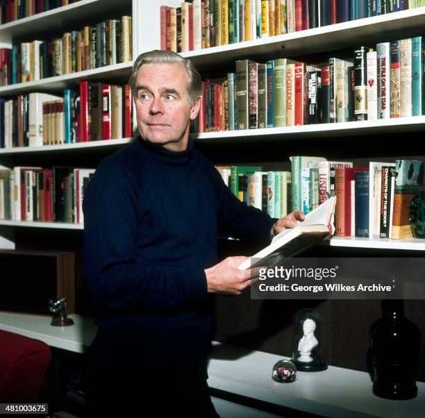 English actor Ian Carmichael, OBE poses with a book in his hands, London, England, 1975.