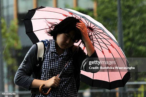 Woman tries to protects her hair style from strong wind as walks in heavy rain delivered by typhoon Nangka on July 17, 2015 in Himeji, Japan. As...