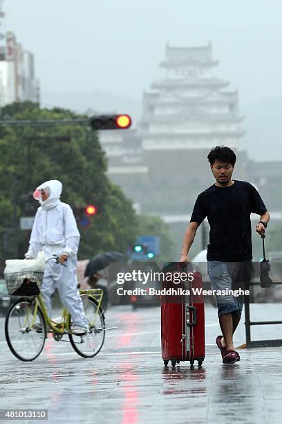 People walk during the strong wind and rain delivered by typhoon Nangka on July 17, 2015 in Himeji, Japan. As Typhoon Nangka made the landfall in...
