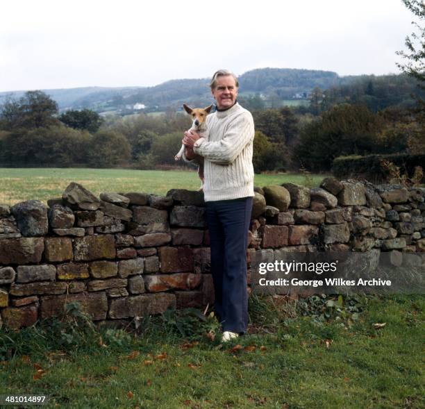 Portrait of English actor Ian Carmichael, OBE as he poses with a dig in his arms, London, England, 1975.