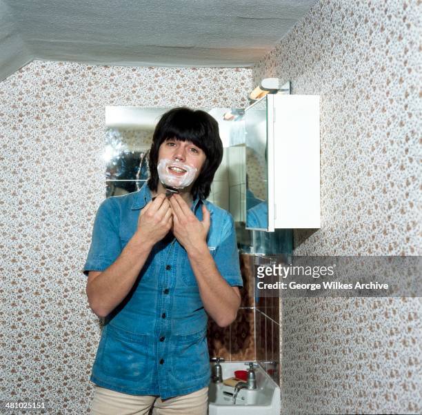 English disc jockey, journalist and television personality Mike Read shaves his chin in a bathroom, London, England, 1981.