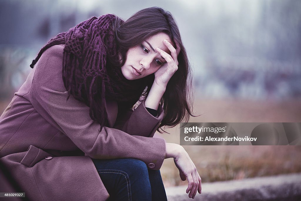 Sad Young Woman Sitting Outdoors