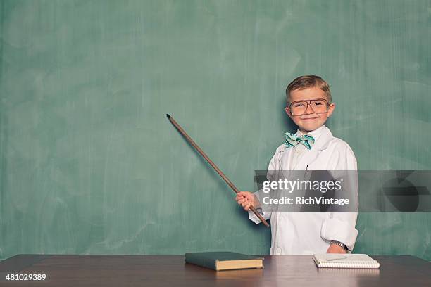 jeune garçon déguisé en scientifique points à tableau - scientifique blouse blanche photos et images de collection