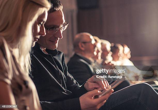 young couple using smartphone between theatre show - klassiek theater stockfoto's en -beelden
