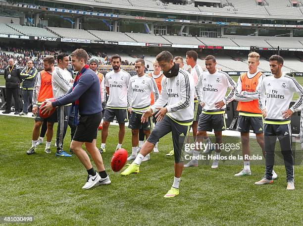 Cristiano Ronaldo of Real Madrid is taught how to kick an Australian Rules football during a Real Madrid training session at Melbourne Cricket Ground...