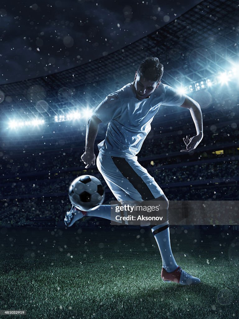 Soccer player tackling a ball on stadium