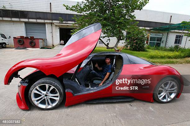 Chen Yinxi poses for a photograph with a car he built in Haikou, south China's Hainan province on July 17, 2015. Chen spent half a year to build the...