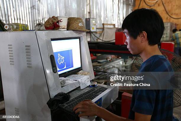 Chen Yinxi, the owner of the electric-car works on his car in a glass factory owned by his father on July 17, 2015 in Haikou in south China's Hainan...