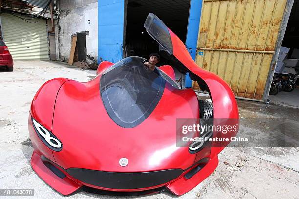 Chen Yinxi, the owner of the electric-car works on his car in a glass factory owned by his father on July 17, 2015 in Haikou in south China's Hainan...