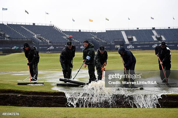 Greenstaff squeegee water into the Burn during the second round of the 144th Open Championship at The Old Course on July 17, 2015 in St Andrews,...