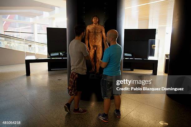 Visitors watch a reconstruction of a Homo Antecessor that lived in Atapuerca Mountains around 800,000 years ago at the Museum of Human Evolution on...