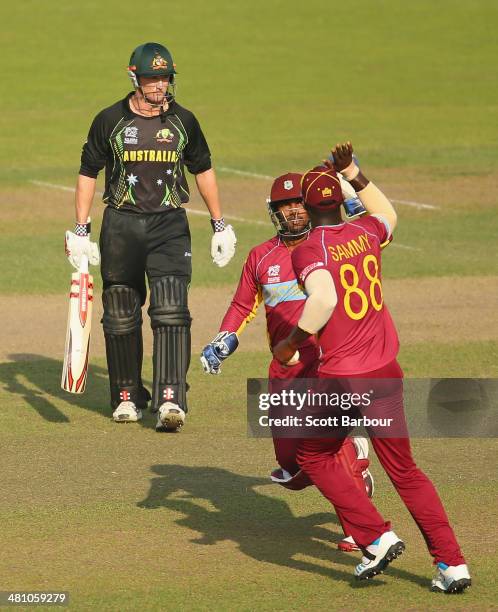 George Bailey of Australia leaves the field as Denesh Ramdin congratulates Darren Sammy of the West Indies for taking the catch during the ICC World...