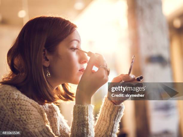 frau hält hand spiegel und die reparatur von make-up. - kajalschminke stock-fotos und bilder