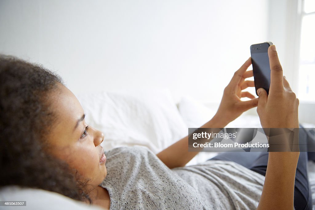 Teenage girl laying down using technology