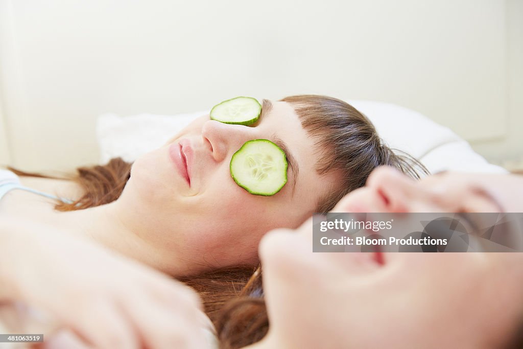 Two friends, one with cucumber on her eyes