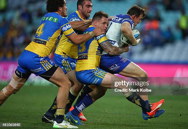 Brad Takairangi, Tim Mannah and Anthony Watmough of the Eels tackle Brett Morris of the Bulldogs during the round 19 NRL match between the Parramatta...