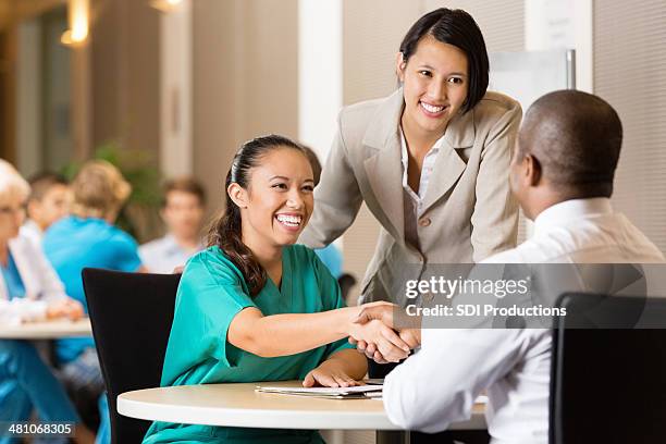 hospital employee and nurse at job interview - asian shaking hands stockfoto's en -beelden