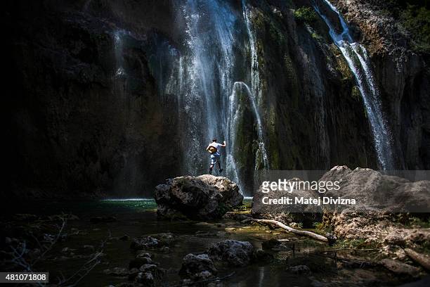 Tourist enjoys sunny day as water falls down from the Big Waterfall at Plitvice Lakes National Park on July 6, 2015 near Plitvicka Jezera, Croatia....