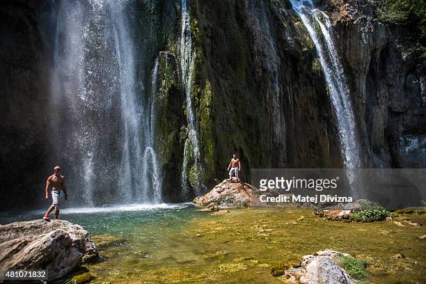 Tourists enjoy sunny day as water falls down from the Big Waterfall at Plitvice Lakes National Park on July 6, 2015 near Plitvicka Jezera, Croatia....