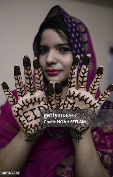 Indian Muslim woman, Feroze Jahan Begum poses showing her hands decorated with mehendi designed with Eid Mubarak wishes during 'Chand Raat' or 'Night...