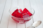 Red jelly cubes in glass bowl with silver spoon