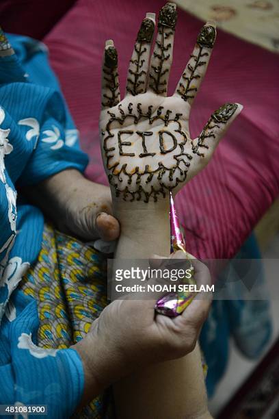 Stylist applies mehendi on the hand of Muslim woman, Feroze Jahan Begum designed with Eid Mubarak wishes during 'Chand Raat' or 'Night of the Moon'...