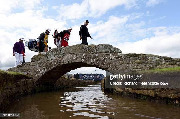 Padraig Harrington of Ireland, caddie Ronan Flood, caddie Ken Herring and Marc Warren of Scotland walk over the Swilcan Bridge that crosses the Burn...