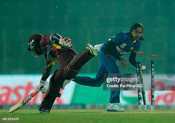 Inoka Ranaweera of Sri Lanka takes off the bails to get Deandra Dottin of West Indies run out during the ICC Women's World Twenty20 match between...