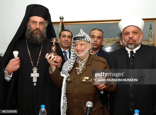In this hand out made available by the Palestinian Press Office Palestinian leader Yasser Arafat holds the 'Holy Fire' brought by Greek Orthodox...
