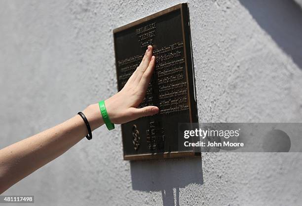 Visitor touches a plaque on the front of the Emanuel AME Church on the one-month anniversary of the mass shooting on July 17, 2015 in Charleston,...