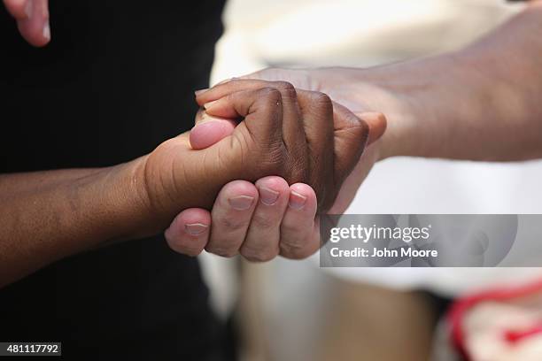 People clasp hands in prayer in front of the Emanuel African Methodist Episcopal Church on July 17, 2015 in Charleston, South Carolina. Visitors from...