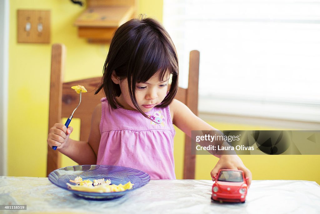 Girl Playing at Breakfast Table