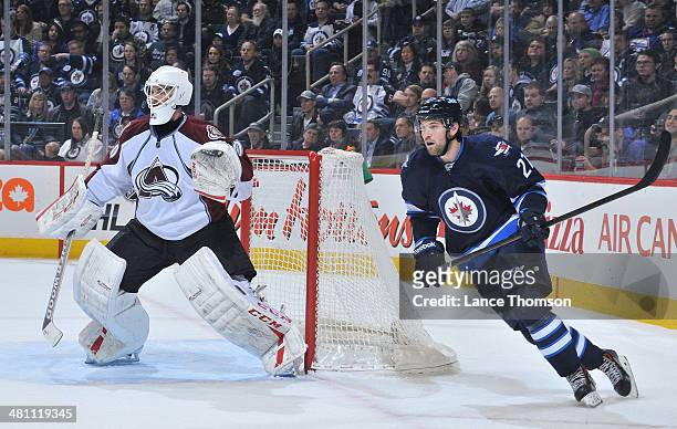 Goaltender Reto Berra of the Colorado Avalanche and Eric Tangradi of the Winnipeg Jets keep an eye on the play during first period action at the MTS...