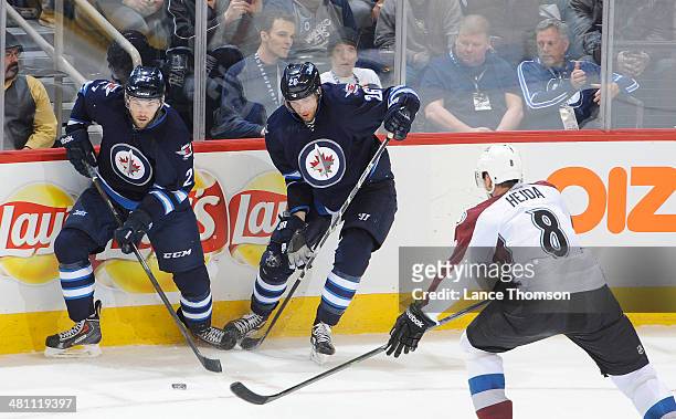 Eric Tangradi of the Winnipeg Jets plays the puck alongside teammate Blake Wheeler as Jan Hejda of the Colorado Avalanche defends during second...