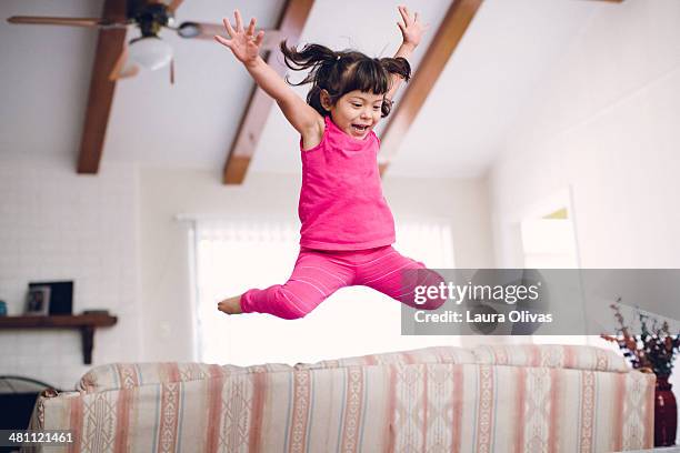 toddler jumps high off the sofa - children jumping stock-fotos und bilder