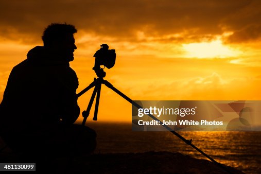 Photographer with camera and tripod at sunset Photographer with camera and tripod at sunset
