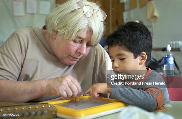 Staff photo by Gregory Rec -- Friday, August 17, 2001 -- 3-year-old Jose Rodriguez plays with Shirley Firak at a Headstart program in Milbridge that...