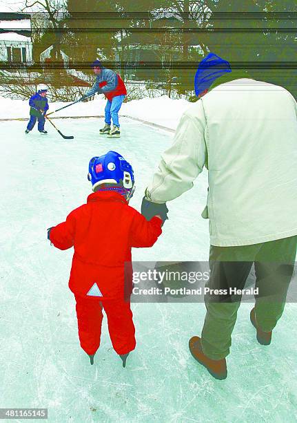 Staff Photo by Jill Brady, Mon, Feb 17, 2003: Chip Knowles gives his son, Matty, 4 1/2, a hand while skating at a backyard rink owned by Rolf and...