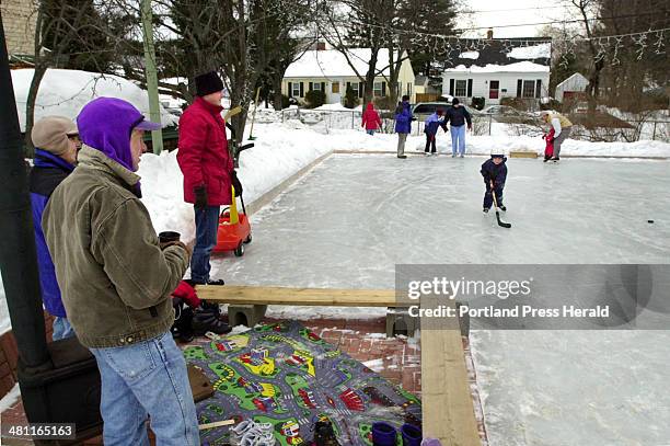 Staff Photo by Jill Brady, Mon, Feb 17, 2003: Michael and Jennifer Westphal, left, of Topsham, keep warm by a woodstove while watching skaters of all...