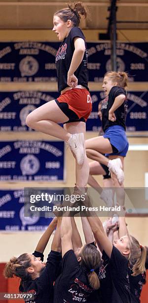 Staff Photo by Gregory Rec, Thursday, January 30, 2003: Wells High School sophomore Elizabeth Condon is lifted high by her cheerleading teammates...