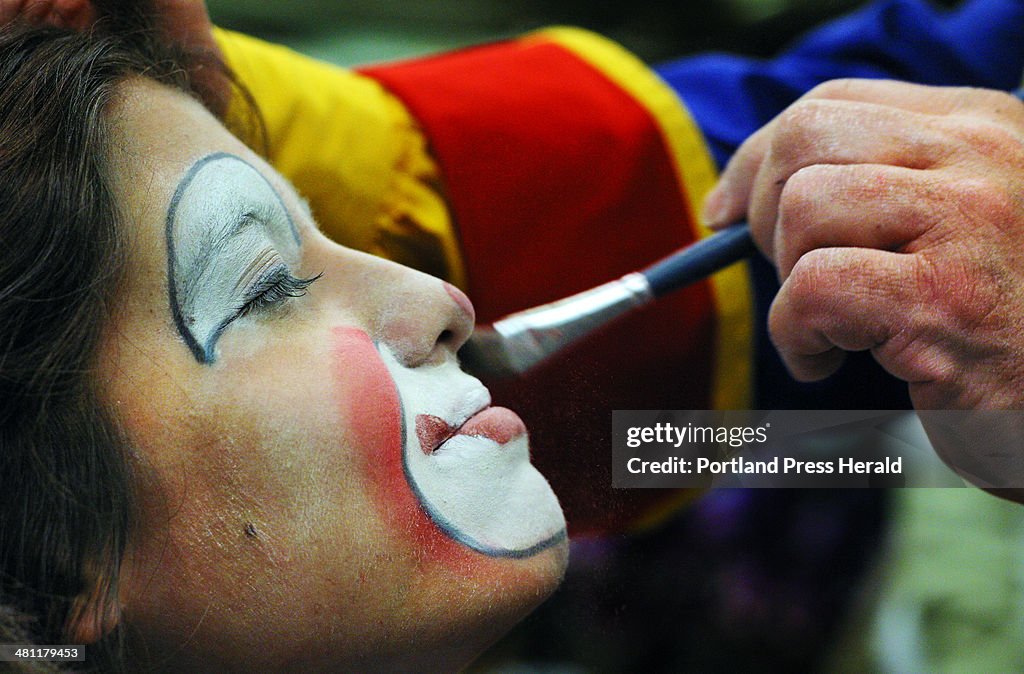 Becca Tolbert gets her face dusted of powder after being made up as a clown at the Kora Shrine Circu