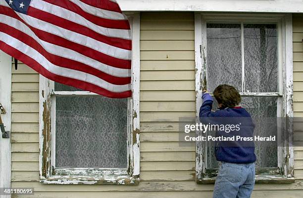 Staff Photo by Gregory Rec, Thu, Mar 30, 2000: A flag flows in the breeze while Mary Cade scrapes paint off a window sill Thursday at the Corsican...