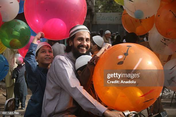 Pakistani kids hold balloons as they leave a mosque after Eid al-Fitr Prayers in Karachi, Pakistan, on July 18, 2015. Muslims around the world...